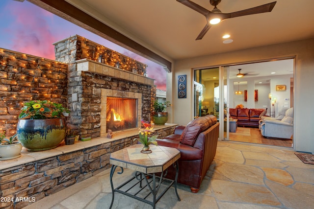 living room with a stone fireplace and ceiling fan