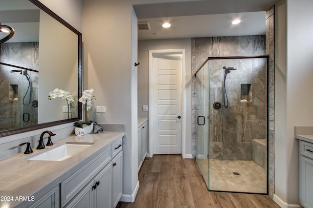 bathroom with hardwood / wood-style flooring, a shower with door, and vanity