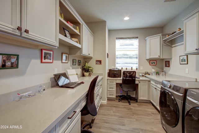 laundry room with light hardwood / wood-style floors, washing machine and dryer, and cabinets