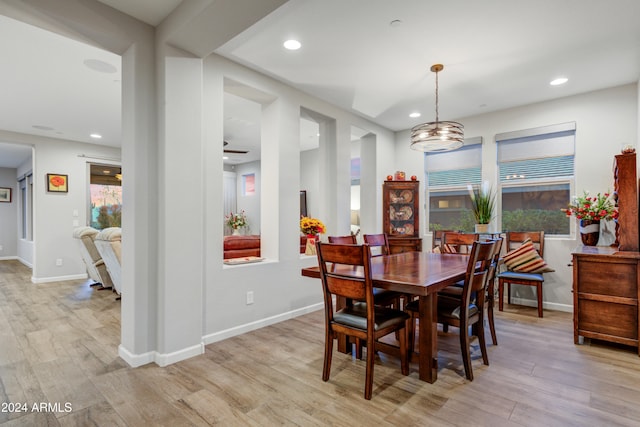 dining area featuring light wood-type flooring and ceiling fan with notable chandelier