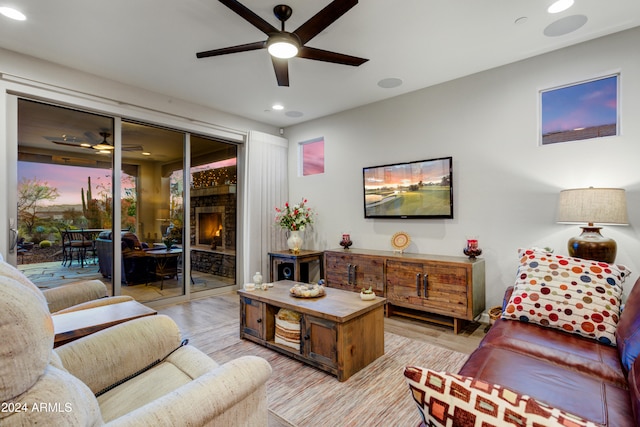 living room featuring a fireplace, light hardwood / wood-style floors, and ceiling fan