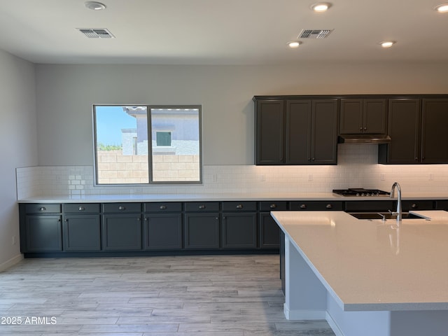 17324 W Royal Palm Rd, Waddell, AZ 85355 - kitchen featuring a sink, stainless steel gas stovetop, light countertops, backsplash, and light wood-type flooring
