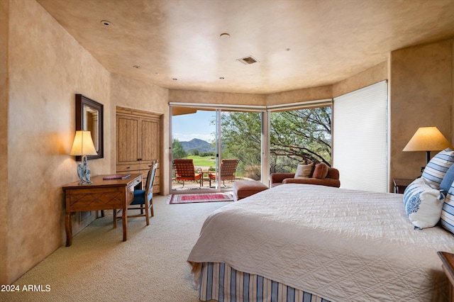 bedroom with carpet floors, a mountain view, and access to exterior