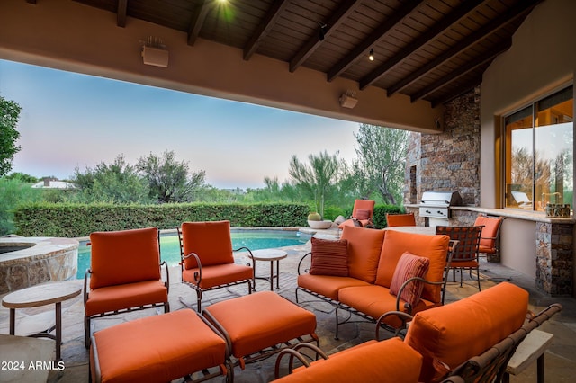 patio terrace at dusk with a grill, an outdoor living space, and an outdoor kitchen