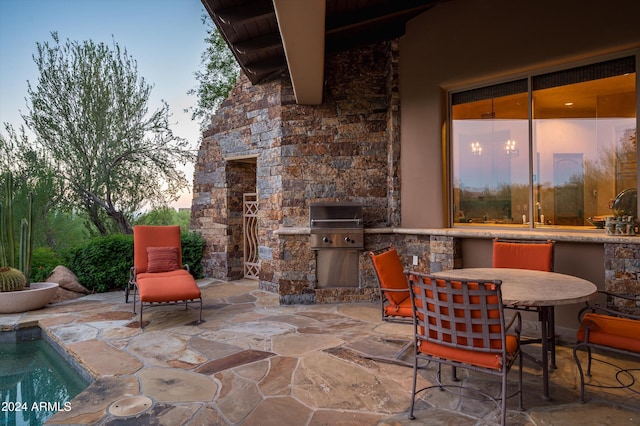 patio terrace at dusk featuring an outdoor kitchen and grilling area