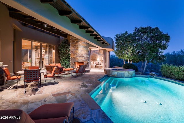 pool at twilight featuring a patio, an in ground hot tub, and an outdoor living space