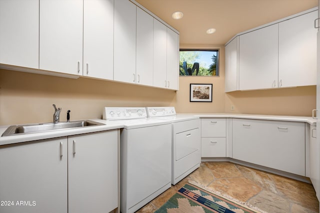 clothes washing area featuring sink, washing machine and clothes dryer, and cabinets