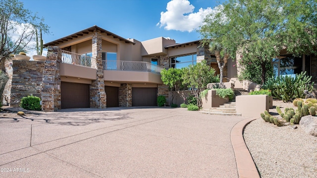 adobe home featuring a balcony and a garage