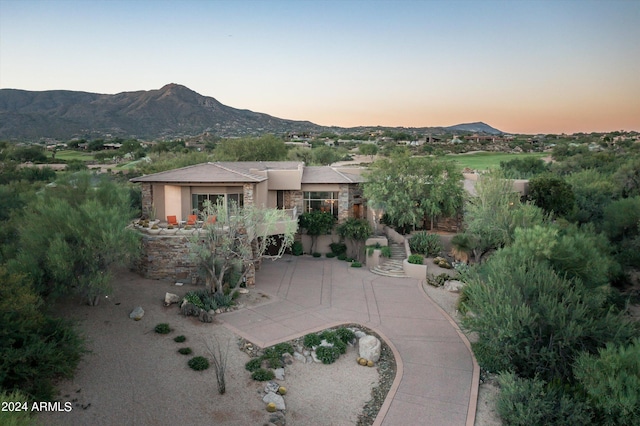 back house at dusk with a mountain view and a patio