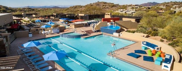 view of swimming pool with a hot tub, a mountain view, and a patio area