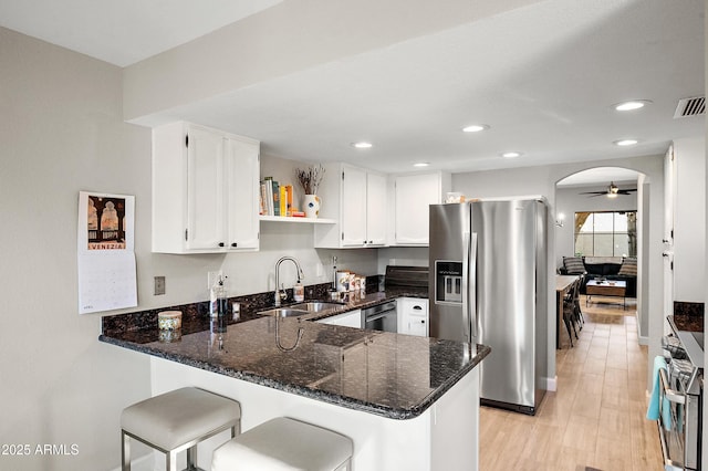 kitchen featuring sink, appliances with stainless steel finishes, dark stone countertops, white cabinets, and kitchen peninsula