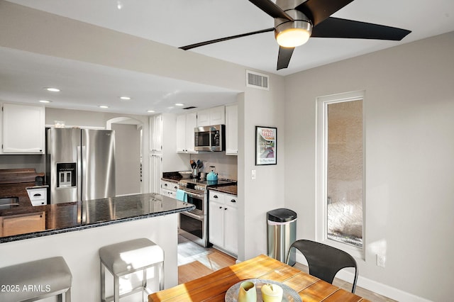 kitchen with white cabinetry, appliances with stainless steel finishes, kitchen peninsula, and light hardwood / wood-style flooring