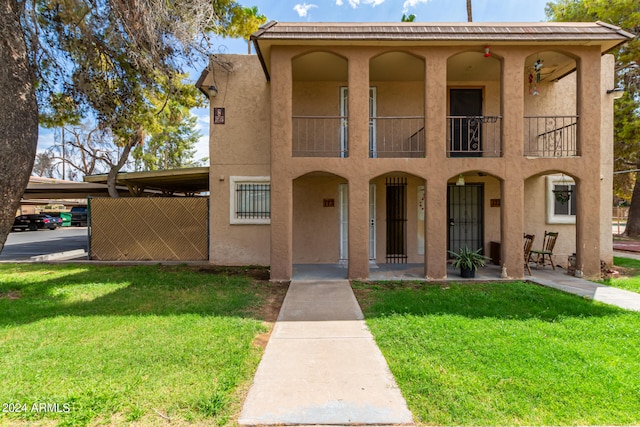 view of front of home featuring a carport, a balcony, and a front yard