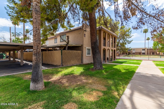 view of property exterior featuring stucco siding, a yard, and fence