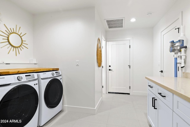 clothes washing area with separate washer and dryer, light tile patterned floors, and cabinets