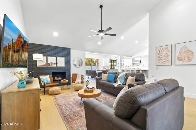 living room with a fireplace, light wood-type flooring, high vaulted ceiling, and ceiling fan