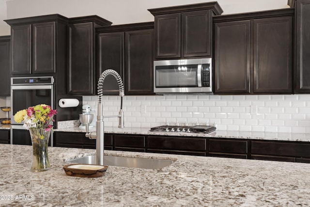 kitchen featuring dark brown cabinets, decorative backsplash, sink, and stainless steel appliances