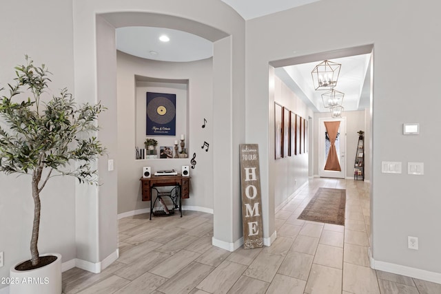 corridor featuring an inviting chandelier and light hardwood / wood-style flooring