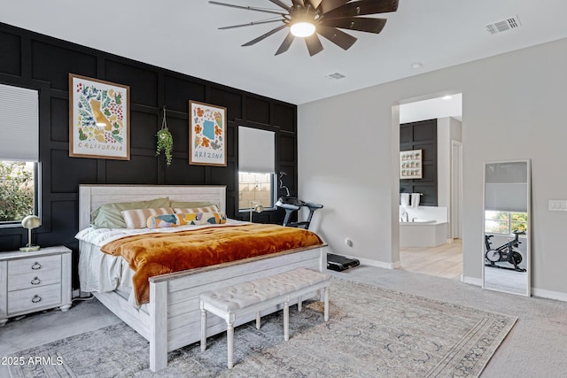 bedroom with light carpet, ensuite bath, and ceiling fan