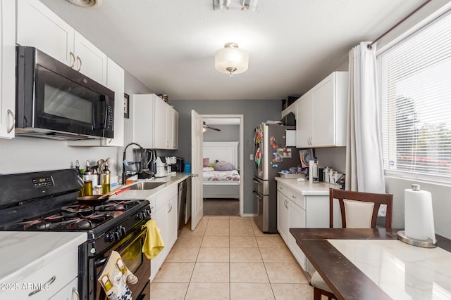 kitchen with light tile patterned floors, sink, ceiling fan, white cabinetry, and black appliances