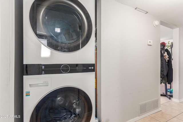 washroom with stacked washer / drying machine and light tile patterned floors