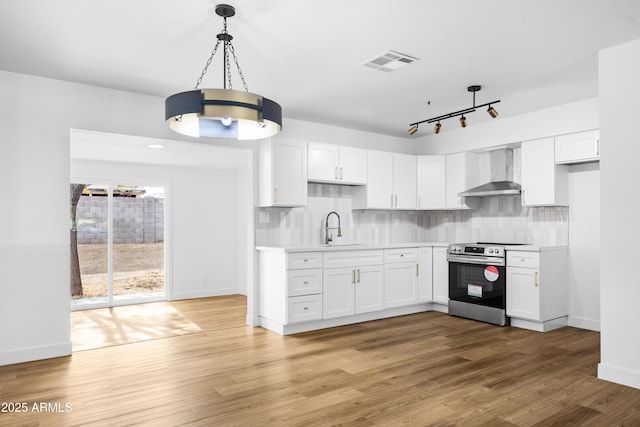 kitchen with stainless steel electric stove, wall chimney exhaust hood, pendant lighting, and white cabinets