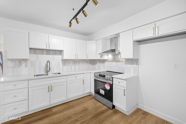 kitchen featuring white cabinetry, electric range, sink, and wall chimney range hood