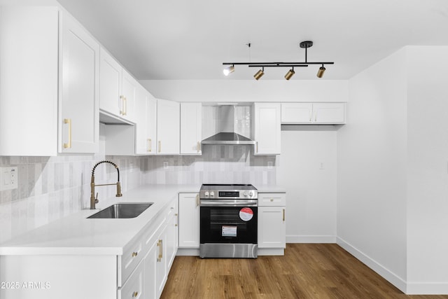 kitchen with tasteful backsplash, wall chimney exhaust hood, stainless steel electric stove, hardwood / wood-style flooring, and white cabinetry