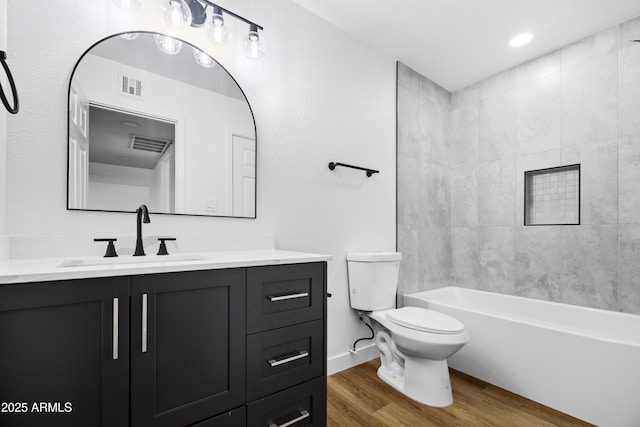 full bathroom featuring tiled shower / bath, hardwood / wood-style floors, vanity, and toilet