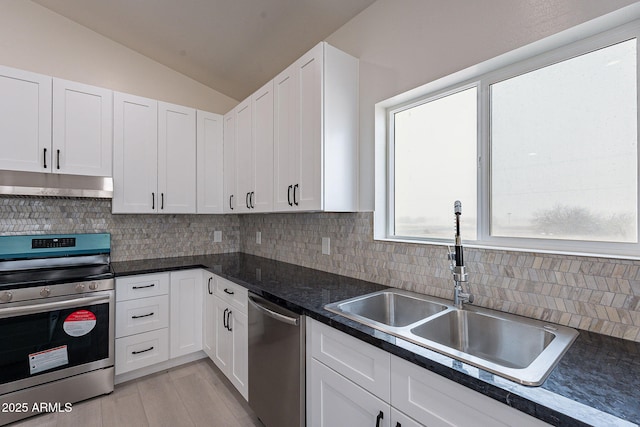 kitchen with vaulted ceiling, appliances with stainless steel finishes, tasteful backsplash, white cabinetry, and sink