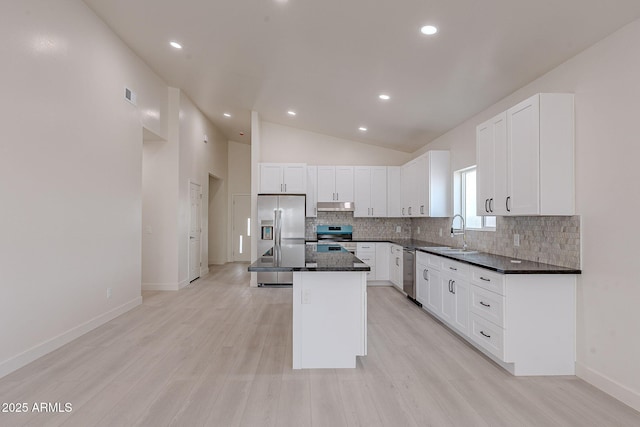 kitchen with high vaulted ceiling, sink, white cabinets, a center island, and stainless steel appliances