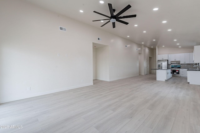 unfurnished living room with ceiling fan, sink, and light wood-type flooring