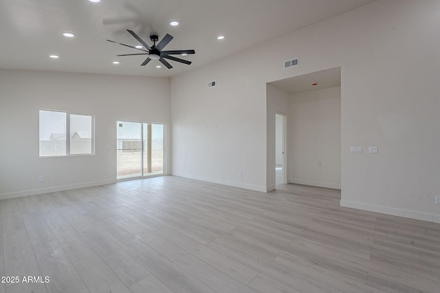 unfurnished room with light hardwood / wood-style floors, ceiling fan, and a high ceiling