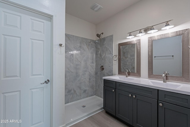 bathroom featuring hardwood / wood-style flooring, vanity, and a tile shower