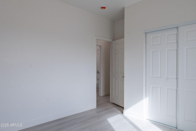 unfurnished bedroom with a closet and light wood-type flooring