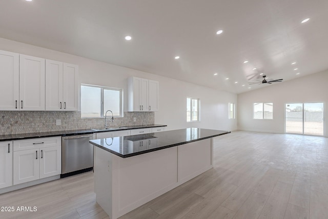 kitchen featuring lofted ceiling, sink, a center island, white cabinets, and stainless steel dishwasher