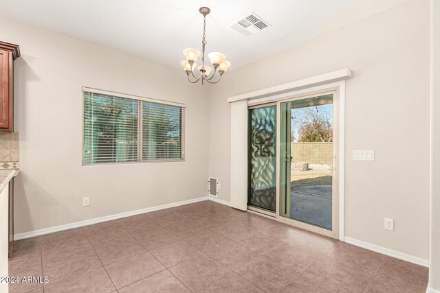 tiled empty room with an inviting chandelier