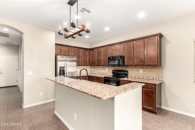 kitchen featuring pendant lighting, a kitchen island with sink, black appliances, sink, and tasteful backsplash