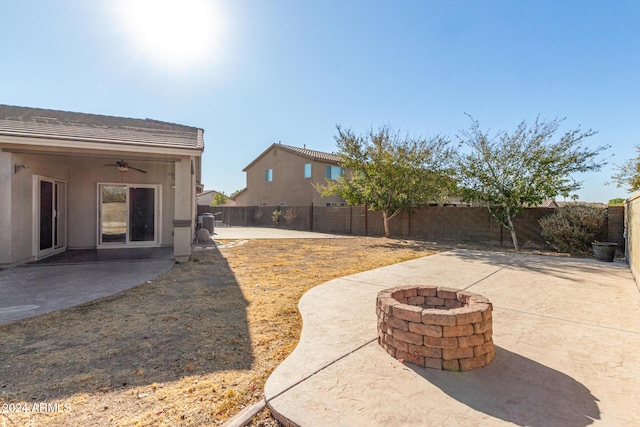 view of yard featuring ceiling fan, an outdoor fire pit, and a patio