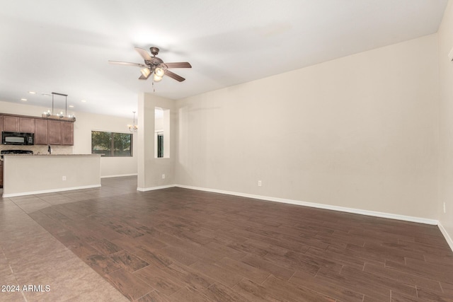 unfurnished living room featuring dark hardwood / wood-style flooring and ceiling fan with notable chandelier