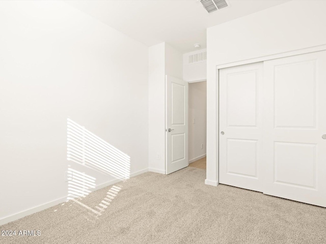 unfurnished bedroom with light carpet and a closet