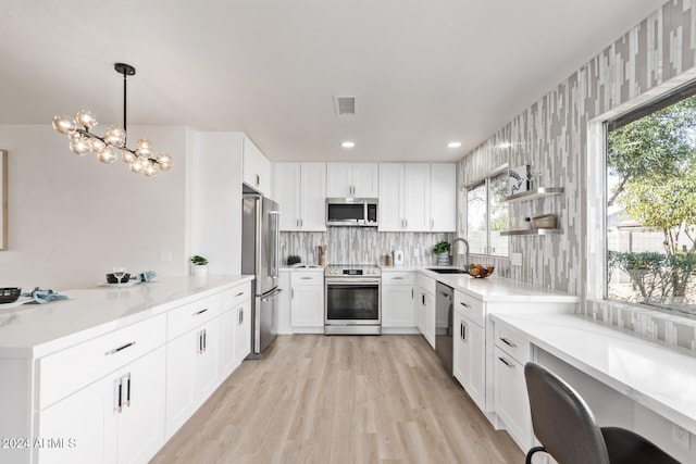 kitchen featuring pendant lighting, appliances with stainless steel finishes, sink, and white cabinets