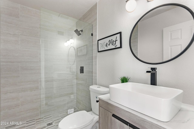 bathroom with vanity, a tile shower, and toilet