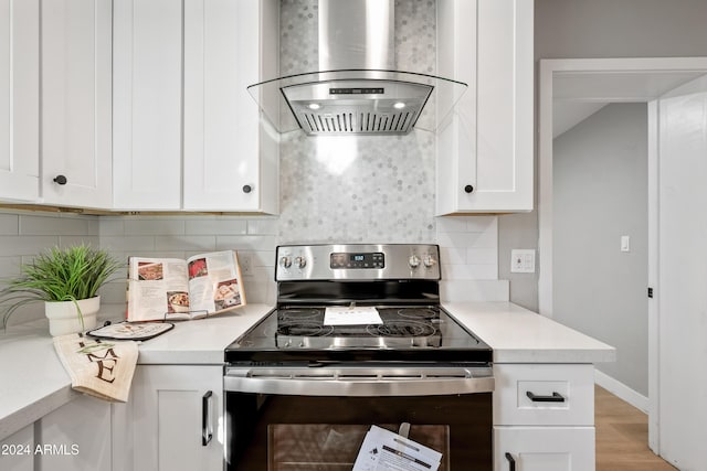 kitchen with island exhaust hood, decorative backsplash, white cabinets, light hardwood / wood-style floors, and stainless steel electric range oven