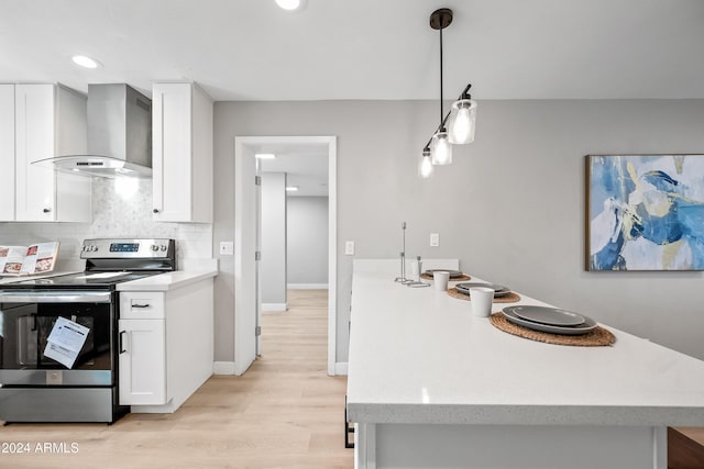 kitchen with white cabinetry, wall chimney range hood, light hardwood / wood-style floors, decorative light fixtures, and stainless steel electric stove