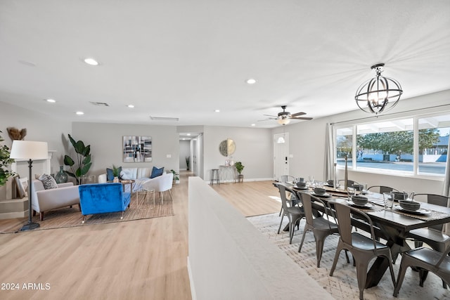 dining area with ceiling fan with notable chandelier and light wood-type flooring