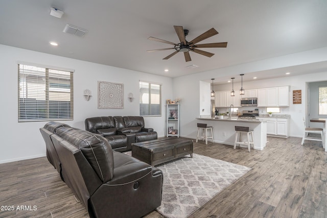 living room featuring sink, ceiling fan, and light hardwood / wood-style flooring