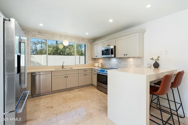 kitchen with backsplash, a breakfast bar, kitchen peninsula, sink, and stainless steel appliances