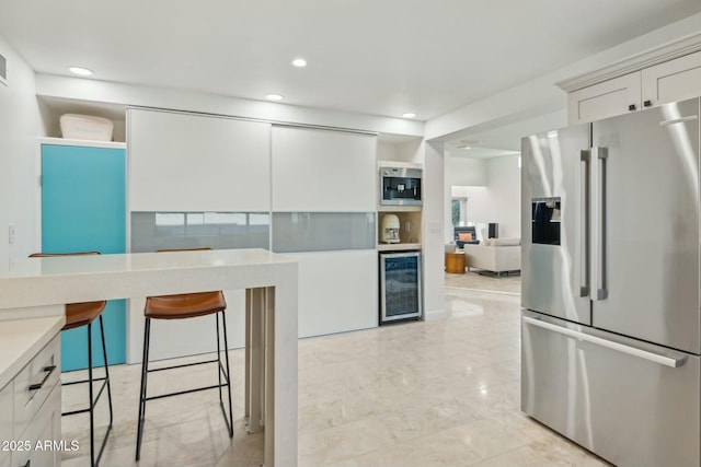 kitchen with a breakfast bar, beverage cooler, white cabinets, and high end refrigerator