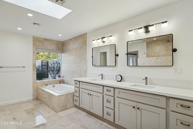 bathroom featuring tiled bath, vanity, and a skylight